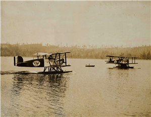 Two single propeller seaplanes on a still body of water
